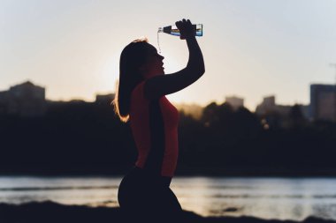 Eğitimden sonra su içen zayıf genç bir kadın..