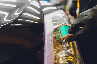 Araba temizleme - Adam arabaya nano koruyucu kaplama uyguluyor. Seçici odak.