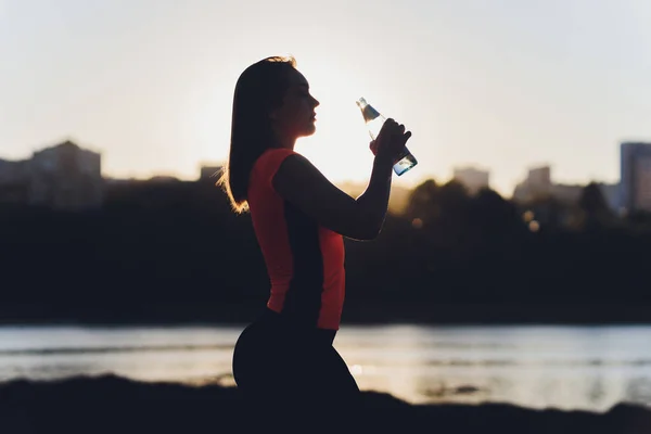 Тонкая молодая женщина пьет воду после тренировки. — стоковое фото