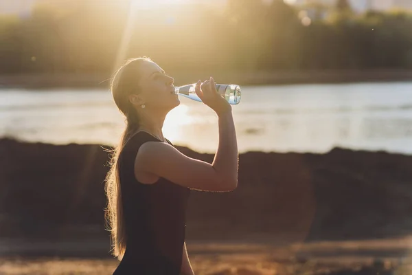 Schlanke junge Frau trinkt nach dem Training Wasser. — Stockfoto