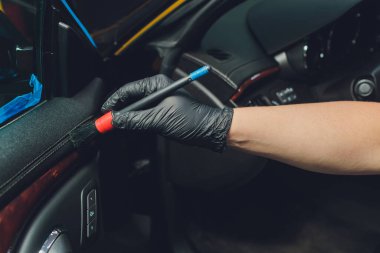 Elbise ve fırçayla araba temizleyen bir adam. Araba tamiri. Seçici odaklanma. Araba tamiri. Fırçayla temizliyorum. İşçi temizliği. Temizlenecek fırça ve temizlik çözeltisi.