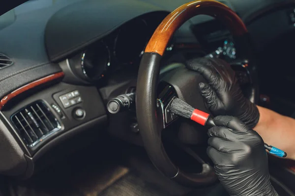 A man cleaning car with cloth and brush. Car detailing. Selective focus. Car detailing. Cleaning with brush. Worker cleaning. Brush and cleaning solution to clean.