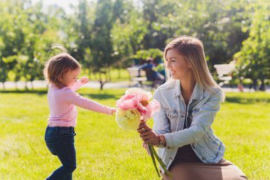 Anneler günün kutlu olsun kızım. Annemi tebrik ediyor ve ona çiçek buketi veriyor. Anne ve kız gülümsüyor ve sarılıyorlar. Aile tatili ve birliktelik.