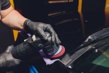 Araba tamiri, oto tamirhanesinde orbital parlatıcıyla el işi. Seçici odak.