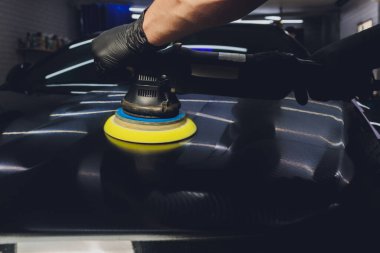 Araba tamiri, oto tamirhanesinde orbital parlatıcıyla el işi. Seçici odak.