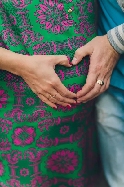 Detailní záběr na břicho těhotné ženy, nošení dlouhých zelených šatů, držení v rukou kytice sedmikrásek venku, nový životní koncept. — Stock fotografie