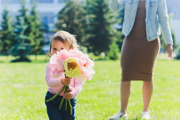 Buon giorno della mamma La figlia si sta congratulando con la mamma e le sta dando un mazzo di fiori di peonie. Mamma e ragazza che sorridono e si abbracciano. Vacanza in famiglia e insieme . — Foto Stock