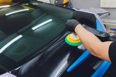 Araba tamiri, oto tamirhanesinde orbital parlatıcıyla el işi. Seçici odak.