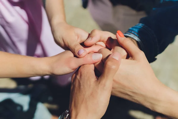 Dos hombres y tres mujeres tomados de la mano en una mesa que implica una relación poliamoria o triángulo amoroso. — Foto de Stock