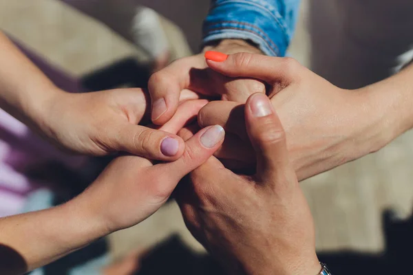 Dos hombres y tres mujeres tomados de la mano en una mesa que implica una relación poliamoria o triángulo amoroso. — Foto de Stock