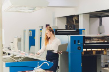 Matbaada çalışan genç bir kadın. Yazdırma Basını.