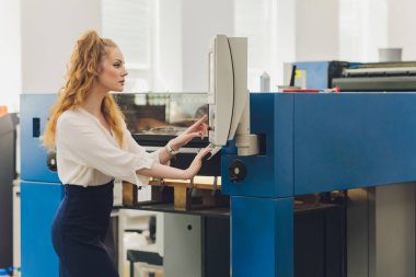 Matbaada çalışan genç bir kadın. Yazdırma Basını.