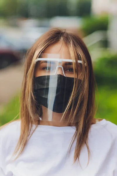 Portrait happy woman wile wearing a face shield for protection from cold and flu and viruses. Young woman with face mask in the street. Woman wearing face mask because of air pollution in the city.