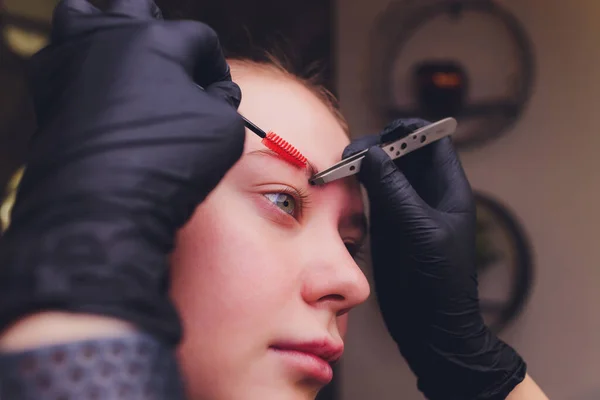 Maquilhagem. Mãos de esteticista fazendo tatuagem de sobrancelha no rosto da mulher. Closeup de especialista fazendo tatuagem de sobrancelha para fêmea. Cosmetologia Tratamento . — Fotografia de Stock