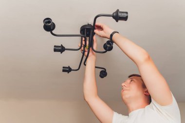 Bir elektrikçi. Tamir işleri. Tavana asılacak avize..