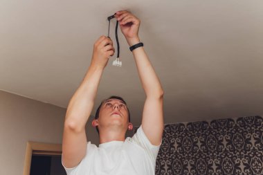 Bir elektrikçi. Tamir işleri. Tavana asılacak avize..