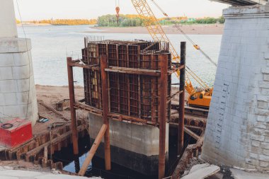 Bitmemiş beton yapı kısmen yeni inşaat alanında mavi branda ile kaplı.