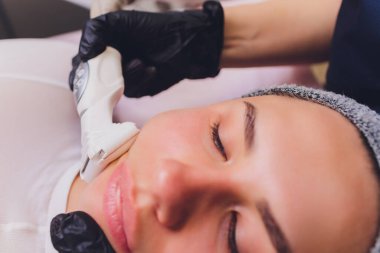 Lenfatik drenaj masajı LPG aygıtı işlemi. Terapist güzellik uzmanı güzellik salonunda manken için canlandırıcı bir yüz masajı yapıyor. Yaklaş, seçici odaklanma.