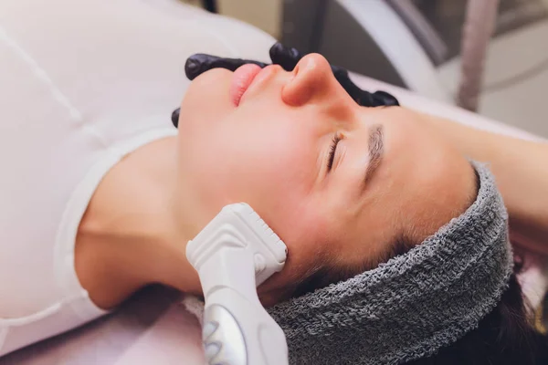 Proceso de drenaje linfático masaje GLP aparato. La esteticista terapeuta hace un masaje facial rejuvenecedor para la modelo en un salón de belleza. Primer plano, enfoque selectivo. — Foto de Stock