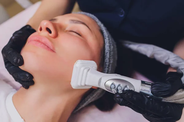 Proceso de drenaje linfático masaje GLP aparato. La esteticista terapeuta hace un masaje facial rejuvenecedor para la modelo en un salón de belleza. Primer plano, enfoque selectivo. — Foto de Stock