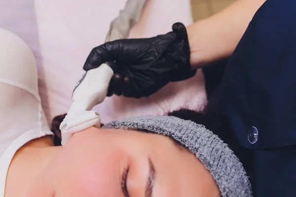 Proceso de drenaje linfático masaje GLP aparato. La esteticista terapeuta hace un masaje facial rejuvenecedor para la modelo en un salón de belleza. Primer plano, enfoque selectivo. — Foto de Stock