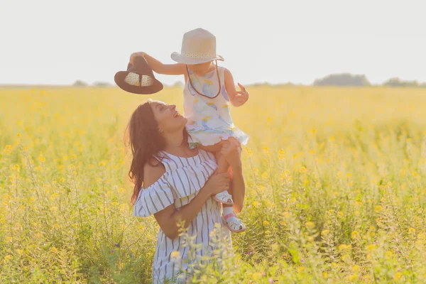 Mooie jonge moeder en haar dochter hebben plezier op het tarweveld. — Stockfoto