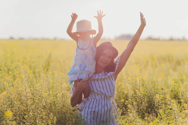 Mooie jonge moeder en haar dochter hebben plezier op het tarweveld. — Stockfoto