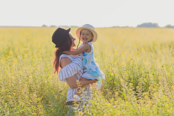 Mooie jonge moeder en haar dochter hebben plezier op het tarweveld. — Stockfoto