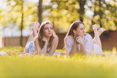 Gülümseyen kadın dışarıda öğle yemeği molası veriyor, çimlerin üzerinde oturuyor ve yemek yiyor..