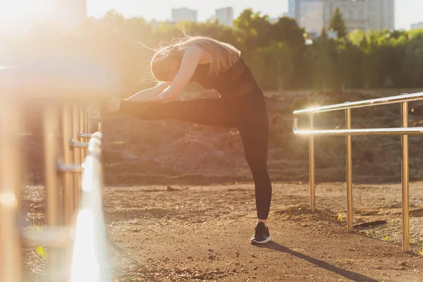 Šťastná úspěšná sportovkyně zvedající ruce k obloze na zlatém pozadí osvětlení západu slunce v létě. Fitness sportovec se zbraněmi se slaví cíle po sportovním cvičení a cvičení venku. Kopírovat prostor. — Stock fotografie