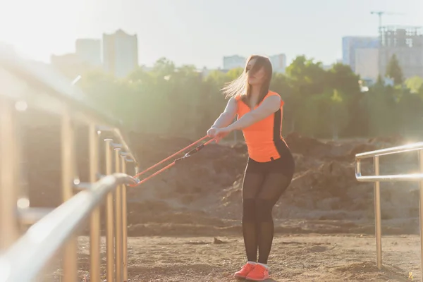 Junge, athletische Frau macht Übungen mit einem Gummiband. Fitness. Freizeit. — Stockfoto