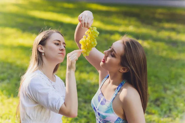 外でリラックスしたランチ休憩をしている笑顔の女性は、彼女が草の上に座って食べています. — ストック写真