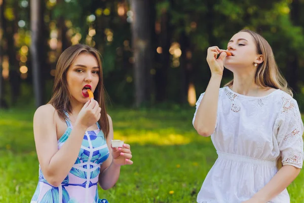 Usmívající se žena má relaxační přestávku na oběd venku, sedí na trávě a jí. — Stock fotografie