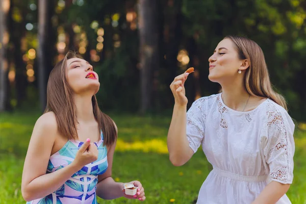 Mujer sonriente teniendo una pausa relajante para almorzar al aire libre, ella está sentada en la hierba y comiendo . — Foto de Stock