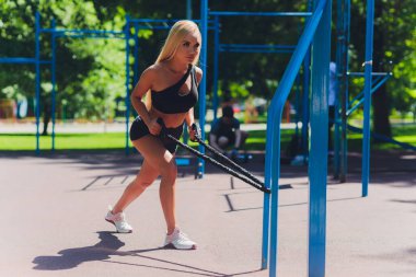 Muhteşem formda kız köprüde lastik direniş bandıyla esneme hareketleri yapıyor. Metin için boşluk.