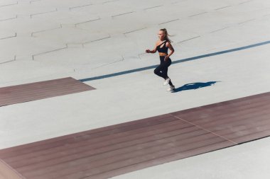 Koşan kadın. Koşucu gün doğumunda koşuyor. Şehrin dışında bir rıhtımda kadın fitness modeli eğitimi. Spor yaşam tarzı.