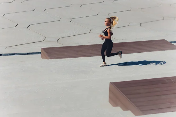 Löpande kvinna. Runner joggar på soluppgången. Kvinnlig fitness modell utbildning utanför i staden på en kaj. Idrottslivsstil. — Stockfoto