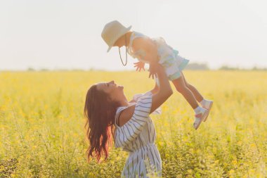 Güzel genç anne ve kızı buğday tarlasında eğleniyorlar..