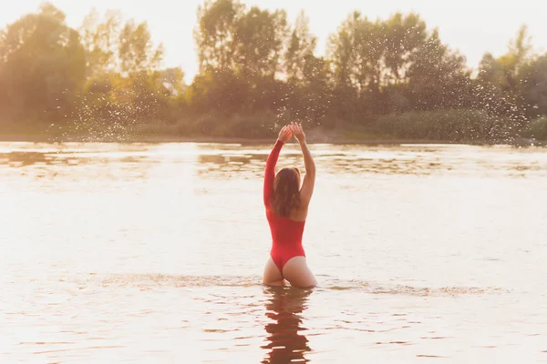 Mulher bonita em maiô vermelho posando perto do rio. Estilo de vida verão. — Fotografia de Stock