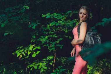 Yeşil parkta egzersiz yapan, kollarını esneten gülümseyen kız. Genç fitness kadını dışarıda esneme egzersizleri yapıyor. Doğadaki sporcu kadın. Sağlıklı yaşam tarzı.