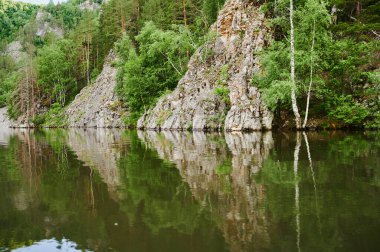 Öndeki yeşil tarlaların doğal görüntüsü ve güneşli bir yaz gününde arka plandaki uçurum ve tepelerin dağları..