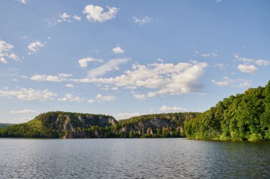 Öndeki yeşil tarlaların doğal görüntüsü ve güneşli bir yaz gününde arka plandaki uçurum ve tepelerin dağları..