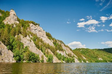 Öndeki yeşil tarlaların doğal görüntüsü ve güneşli bir yaz gününde arka plandaki uçurum ve tepelerin dağları..