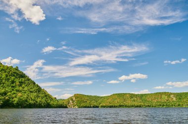 Öndeki yeşil tarlaların doğal görüntüsü ve güneşli bir yaz gününde arka plandaki uçurum ve tepelerin dağları..