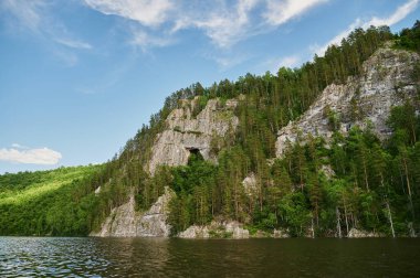 Öndeki yeşil tarlaların doğal görüntüsü ve güneşli bir yaz gününde arka plandaki uçurum ve tepelerin dağları..