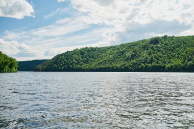 Öndeki yeşil tarlaların doğal görüntüsü ve güneşli bir yaz gününde arka plandaki uçurum ve tepelerin dağları..