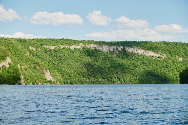 Öndeki yeşil tarlaların doğal görüntüsü ve güneşli bir yaz gününde arka plandaki uçurum ve tepelerin dağları..