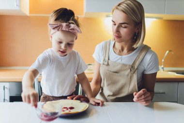 Sevimli bir anne ve kızın portresi mutfakta birlikte bir kız hazırlıyor..