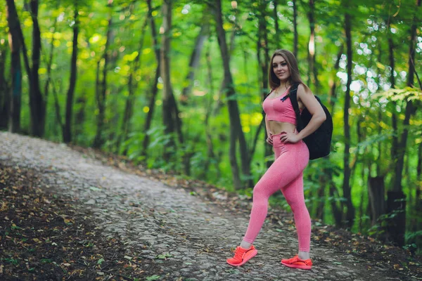 若い笑顔の女性ハイカー登山トレイル、草の丘の上を歩くと、バックパックを着ている。屋外活動、観光コンセプト. — ストック写真