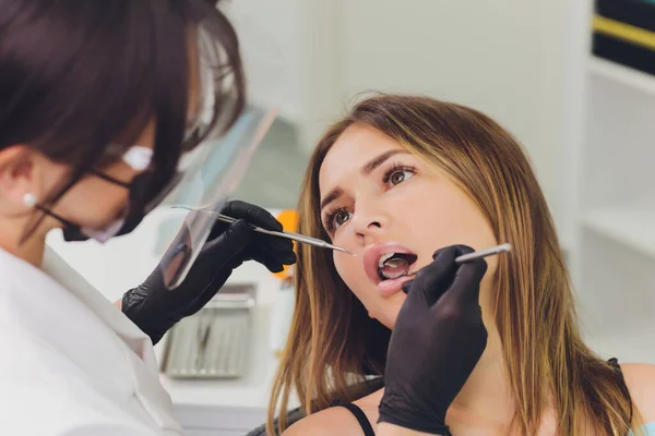Il dentista rileva i denti cariati del paziente sulla sedia dei dentisti. — Foto Stock